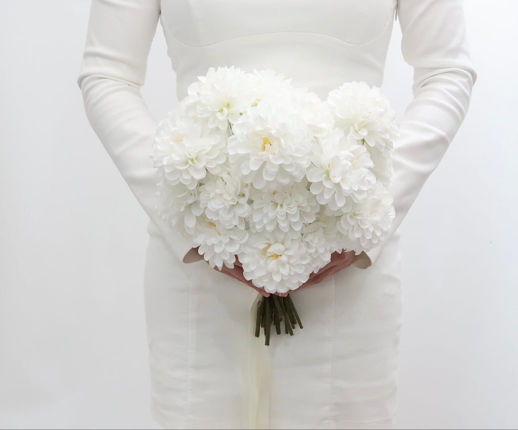 Bride holding a white bridal bouquet against a plain background