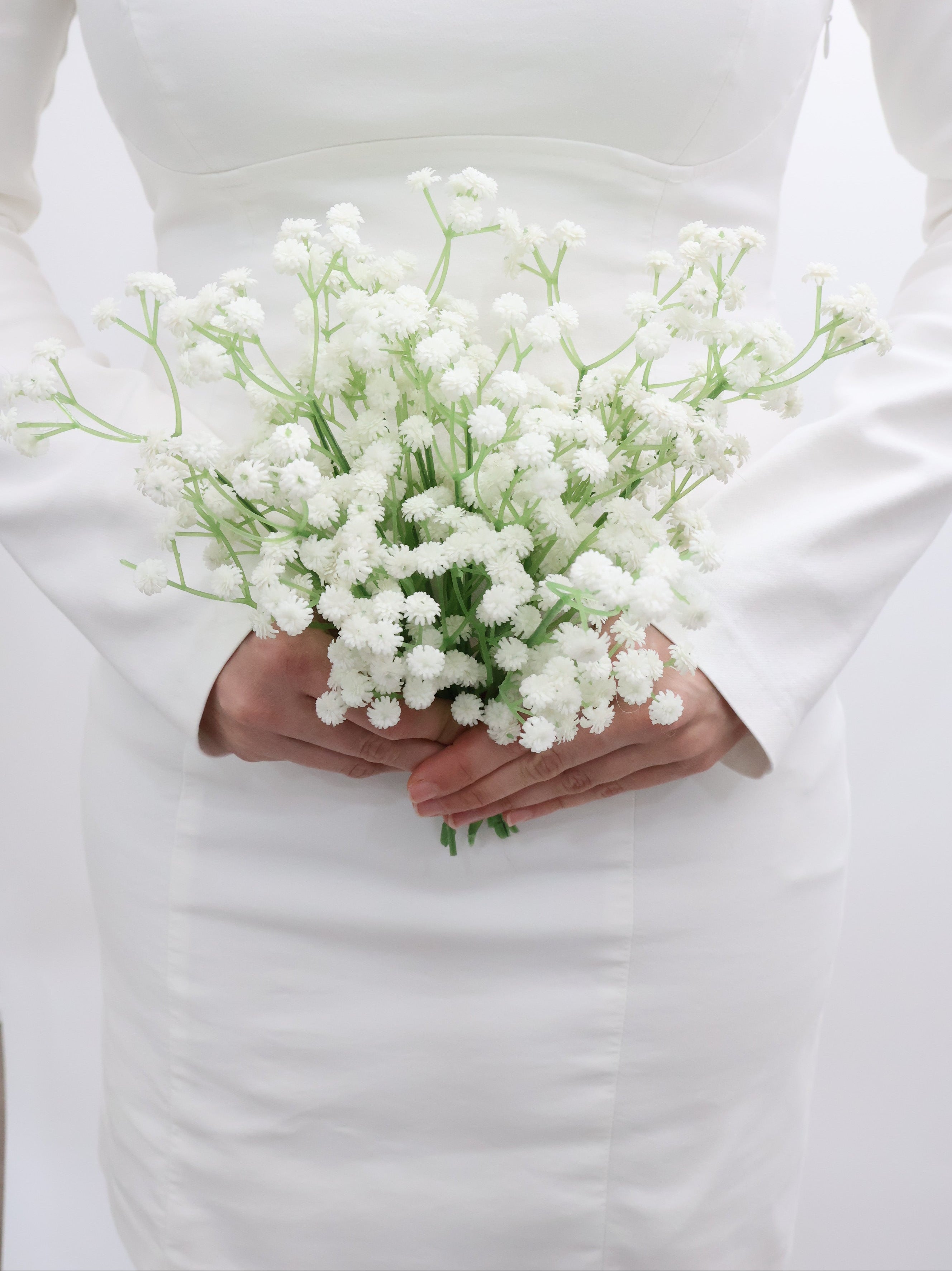 Bridal holding a bouquet of white baby's breath flowers with a wedding dress