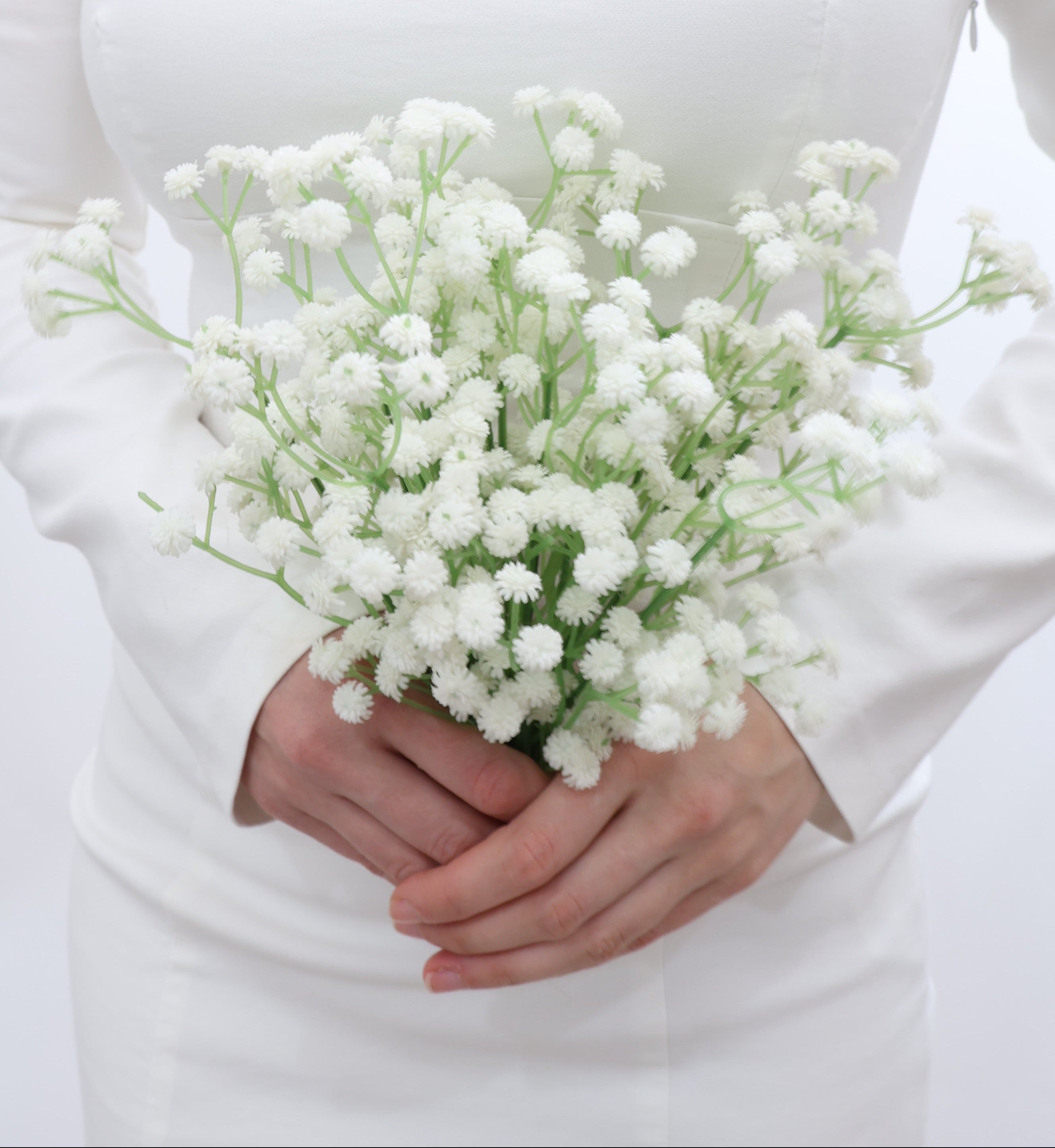 Bridal holding a bouquet of white baby's breath flowers with a wedding dress