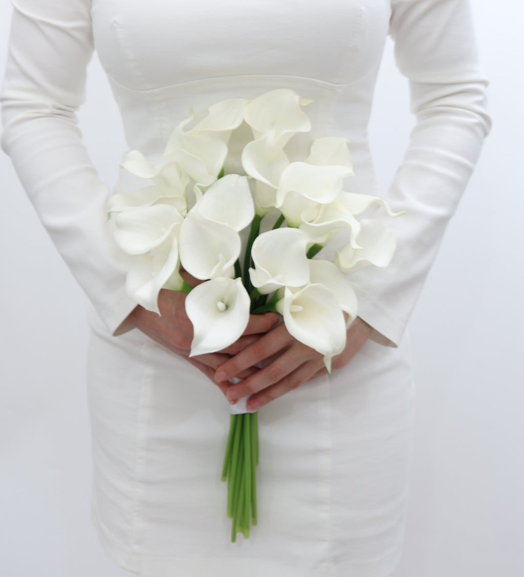 Bride holding a bouquet of white calla lily flowers on a white background