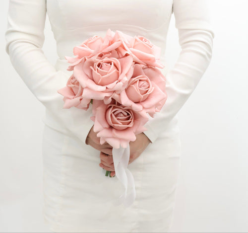 Bouquet of pink roses held by a person wearing a white long-sleeve shirt.